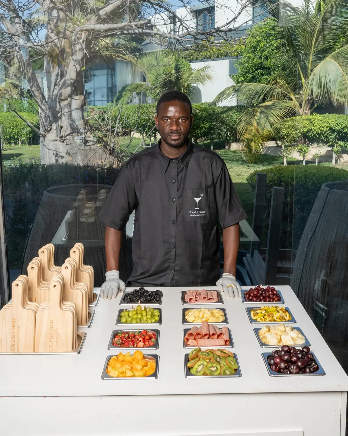 Barman Cocktail Cruise derrière le comptoir du Cruise Bar, bacs de fruits frais et planches en bois gravées