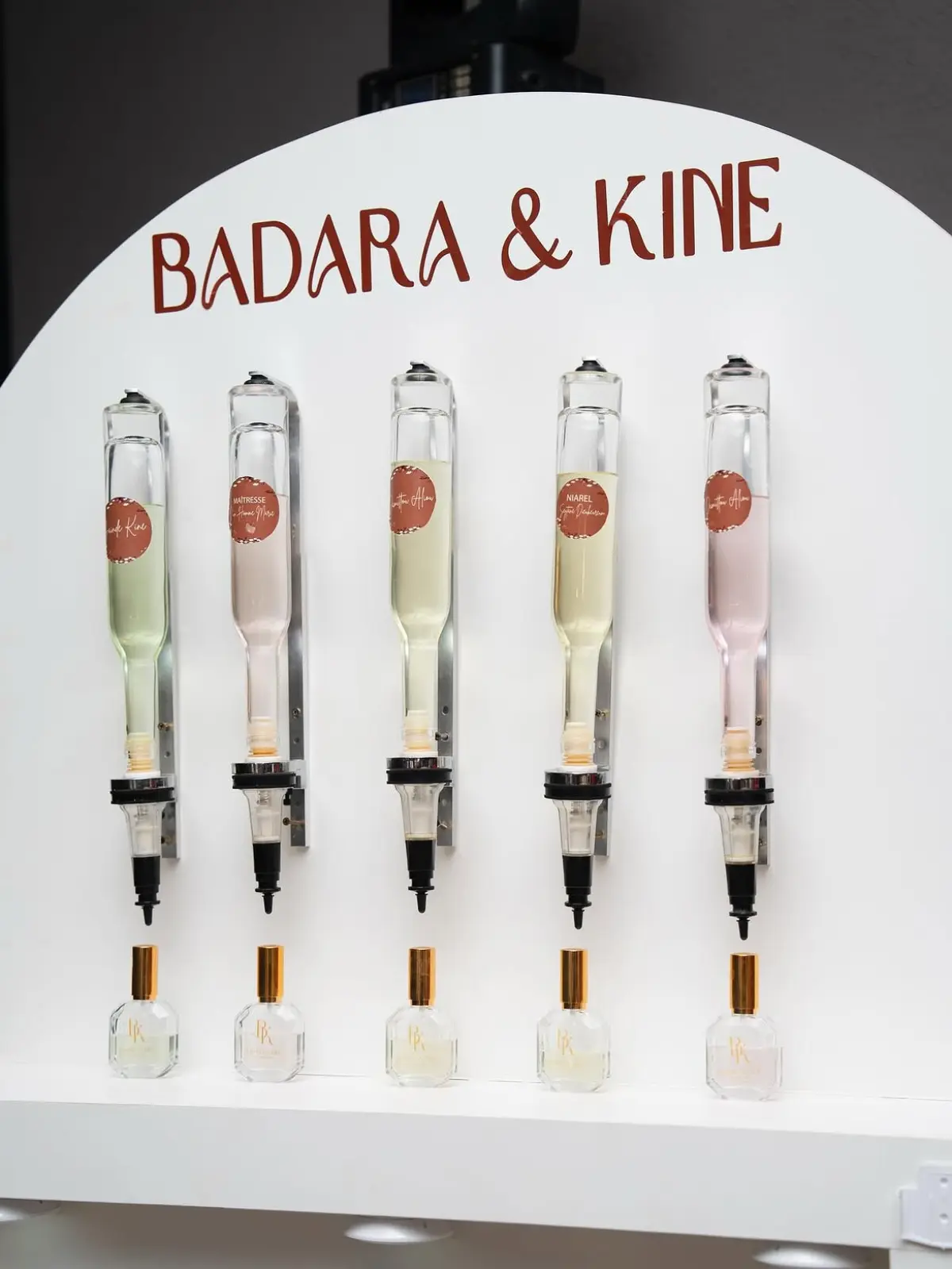 Fontaines à parfum Badara & Kine alignées au-dessus de flacons à capuchon doré