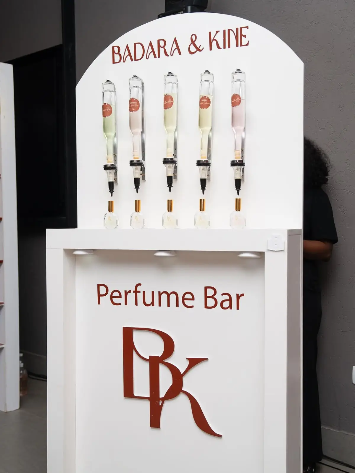 Perfume Bar Badara & Kine : cinq fontaines à parfum au-dessus de flacons dorés sur un comptoir blanc